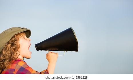 Kid shouting through vintage megaphone. Communication concept. Blue sky background as copy space for your text - Powered by Shutterstock