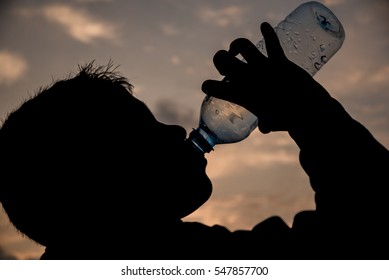 A Kid Silhouette Drinking Water On Sunset