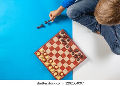 Kid Sitting And Learning To Play Chess Game. Top View