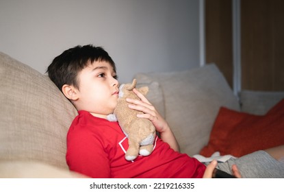 Kid Sitting On Sofa Watching TV, A Boy Holding Remote Control And Looking With Deep In Thought, Positive Child Lying On Sofa Enjoy Watching Cartoon On TV, Kid Relaxing At Home On Weekend