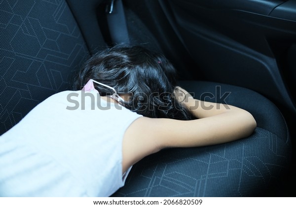 A kid sleeping in the\
car back seat