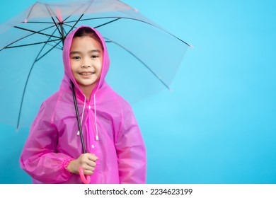 Kid smart and curious , happy children close up cute and cheerful people, holding umbrella and wearing rain coat looking and smile on blue pastel background, new idea creative on isolated blue sky 