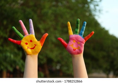 Kid With Smiling Face Drawn On Palms In Green Park, Closeup