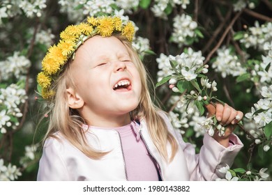 A kid sneezes while walking on the street, a girl with yellow flowers on her head sniffs flowers, a child is allergic to dust and pollen, itchy eyes and nose, allergies and asthma in children - Powered by Shutterstock