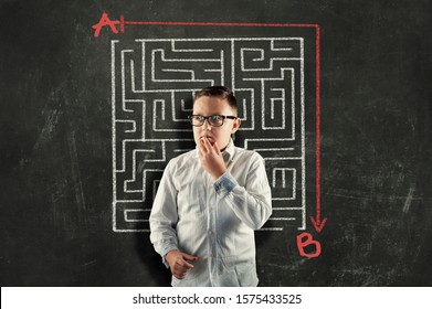 Kid Solving A Maze Using A Shortcut. Maze Drawn On Blackboard .