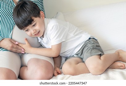 Kid Speaking Telling Stories To Baby Brother In Mommy Mother Belly Uterus.cute Adorable Child Holding Ear Bonded On Tummy Pressing With Hand Speaking Smiling.bedroom Interior,bright Beige Colors.hug