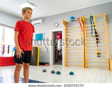 Kid standing in front of mirror in empty gym studio