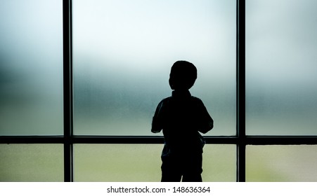 Kid standing and looking out through the window