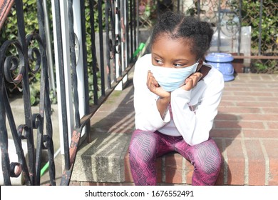 Kid Stting On Brick Stairs Outside Wearing Surgical Mask