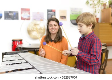Kid studying percussion instrument vibraphone, teacher next to him