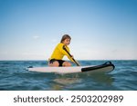 Kid and Summer sea. Child boy paddling on paddle board or sup. Summer vacation with children. Summer lifestyle. Summer Water sport. Kid Boy swimming with paddle board.