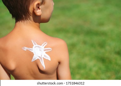 Kid With Sunscreen Of Sun Shape On The Shoulder. Child On The Nature On Sunny Day. Suntan Lotion On Baby Boy Back, Close Up. Skin Care In Summer. Skin Care In Summer. Cream Safety Sunbathing Concept.