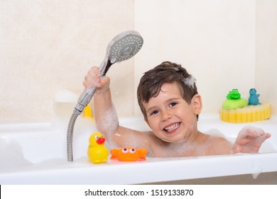 Kid taking bubble bath. Child bathing in bathtub. Little boy playing with water. Rubber duck in foam bath. 
