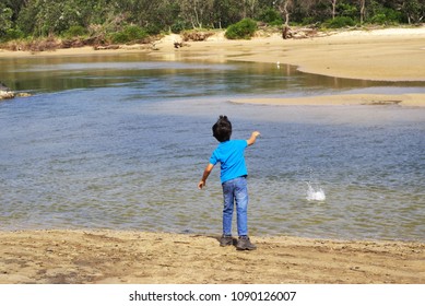 Kid Throwing Stone In Water. Child In Action Of Throwing Stone Or Rock In Water.