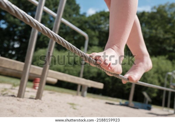 Kid\
tightrope walker balances with bare feet on a\
cord