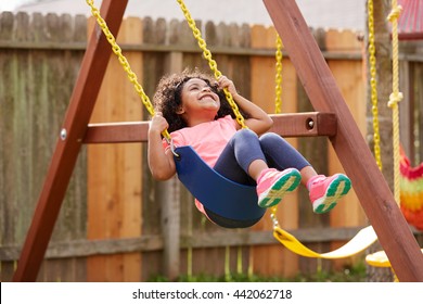 Kid toddler girl swinging on a playground swing in the backyard latin ethnicity