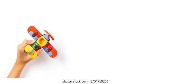 Kid toys banner background. Child hand play with toy airplane on white background. Top view