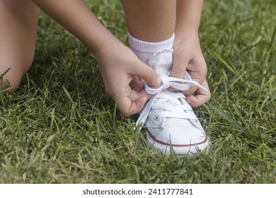 Kid tying shoes. Little girl struggling to tie shoe laces. Child learning fine motor skills. - Powered by Shutterstock