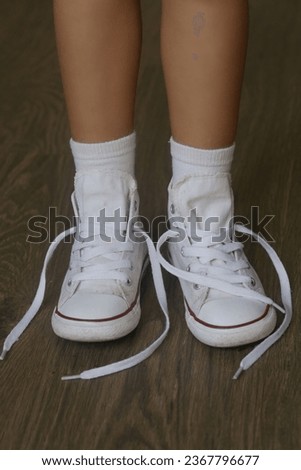 Kid tying shoes. Little girl struggling to tie shoe laces. Child learning fine motor skills.
