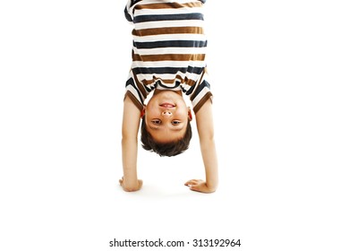 A kid upside down smiling to the camera. Isolated on white background