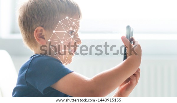 Kid using face id recognition.\
Boy with a smartphone gadget. Digital native children\
concept.