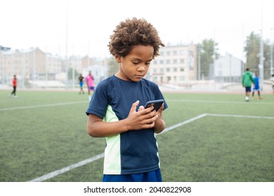 Kid Using Phone. African American Boy Outdoors. Child Calling And Holding Cellphone. Young Person Daily Technology And Internet Outside. Video Call And G5 Network. People Using Smart Phone.