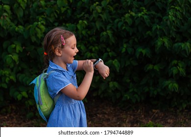 Kid Using Smartwatch Outdoor In Park. Child Talking On Vdeo Call On The Smartphone. Schoolgirl Using Touchscreen Display On Watches Browsing Internet. Smart Wristwatch With GPS Tracker.