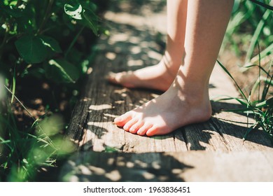 Kid Walking Barefoot On Wood Plank At A Grass Field. Close Up Feet. Detail Of Kids Legs Walking On Wooden Pathway Barefoot. Playful Child On A Garden. Focus On Finger