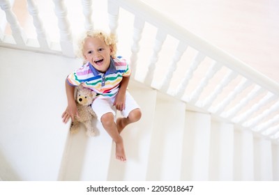 Kid Walking Stairs In White House. Little Boy Playing In Sunny Staircase. Family Moving Into New Home. Child Climbing Steps Of Modern Stairway. Foyer And Living Room Interior. Home Safety For Toddler.