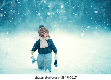 the kid walks in the snow in winter in the white scarf
