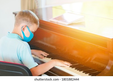 Kid Wearing A Mask And Playing The Piano At Lesson And Event. Kids Back To School Concept
