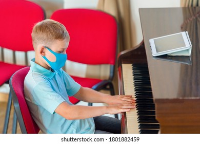 Kid Wearing A Mask And Playing The Piano At Lesson And Event. Kids Back To School Concept
