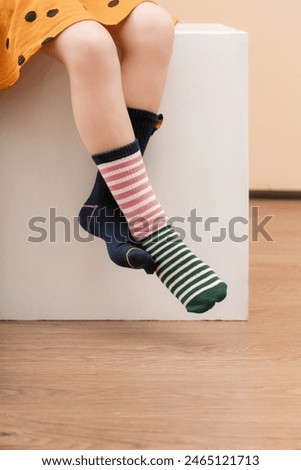 Kid wears different pair of socks. Child foots in mismatched socks, studio photography. Down syndrome awareness concept, odd socks day, anti-bullying week.