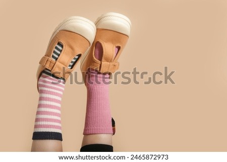 Kid wears different pair of socks. Child foots in mismatched socks, studio photography with copy space. Down syndrome awareness concept, odd socks day, anti-bullying week.