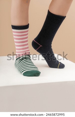 Kid wears different pair of socks. Child foots in mismatched socks, studio photography. Down syndrome awareness concept, odd socks day, anti-bullying week.