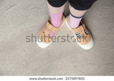 Kid wears different pair of socks. Child foots in mismatched socks, studio photography. Down syndrome awareness concept, odd socks day, anti-bullying week.	