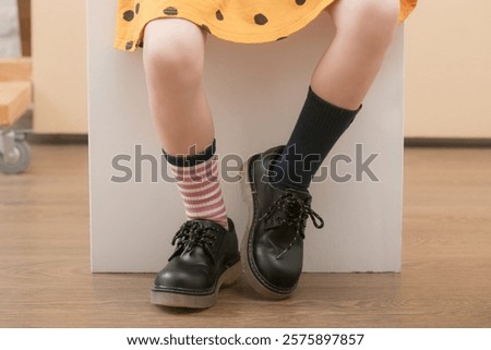 Kid wears different pair of socks. Child foots in mismatched socks, studio photography. Down syndrome awareness concept, odd socks day, anti-bullying week.	