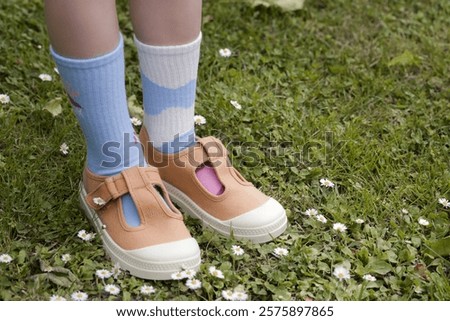 Kid wears different pair of socks. Child foots in mismatched socks, studio photography. Down syndrome awareness concept, odd socks day, anti-bullying week.	