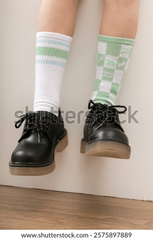 Kid wears different pair of socks. Child foots in mismatched socks, studio photography. Down syndrome awareness concept, odd socks day, anti-bullying week.	