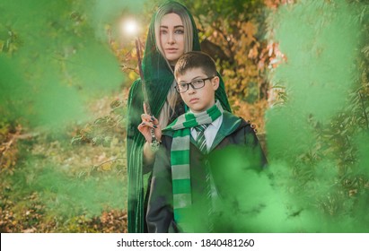 Kid And Witch Woman In Of The Magical Atmosphere. Boy And Mom In Green Robe Magic In The Forest. Family Halloween Time