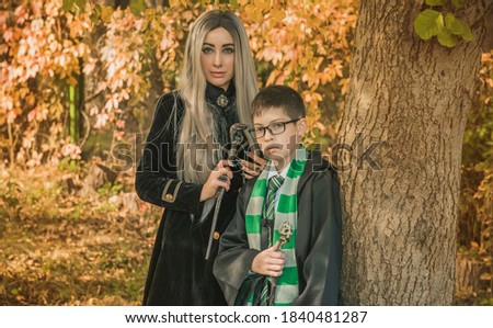 Kid and witch woman in of the magical atmosphere. Boy and mom in green robe magic in the forest. Family Halloween time