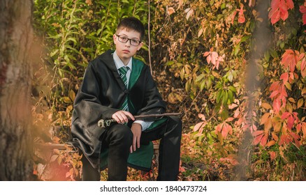 Kid Wizard. A Young Student Of The Magic School Conjures. Boy In Green Robe Magic In The Forest. Halloween Time