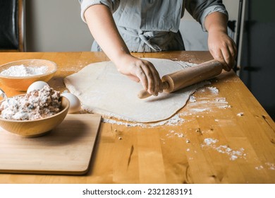 kid-boy making dumplings, pierogi , varenyky, served with cottage cheese lay in sieve. National Ukraine cuisine, natural organic homemade bakery product