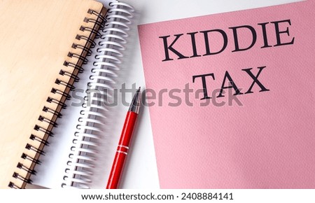 KIDDIE TAX word on pink paper with office tools on white background