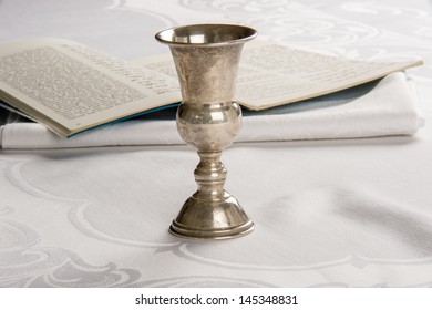 Kiddush cup with Haggadah or prayer book in background
