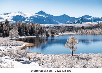 Kidelu lake in Altai mountains, Siberia, Russia. First snow in the autumn forest in sunny day. Snow-covered trees and mountains.