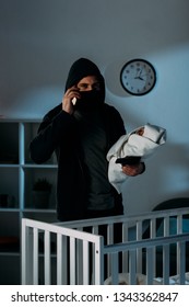 Kidnapper In Mask Holding Infant Child And Talking On Smartphone