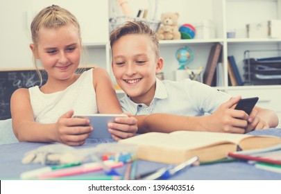 Kids 9-11 Years Old Are Playing Game Together In Their Phones Indoors.