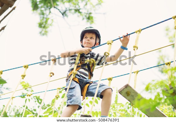 Kids in\
adventure park. Child climbing high wire\
park.