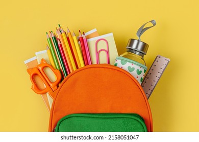 Kids Backpack With School Bus On Yellow Background. Opened School Backpack With Stationery. Primary School Or Kindergarten. 